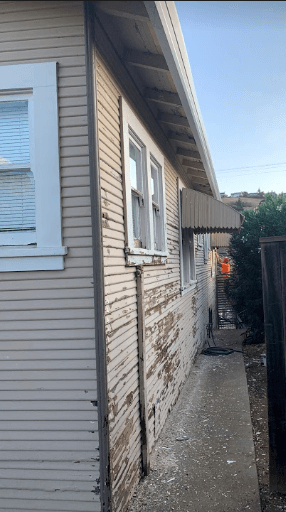 Exterior wood siding mid-project showing prep work